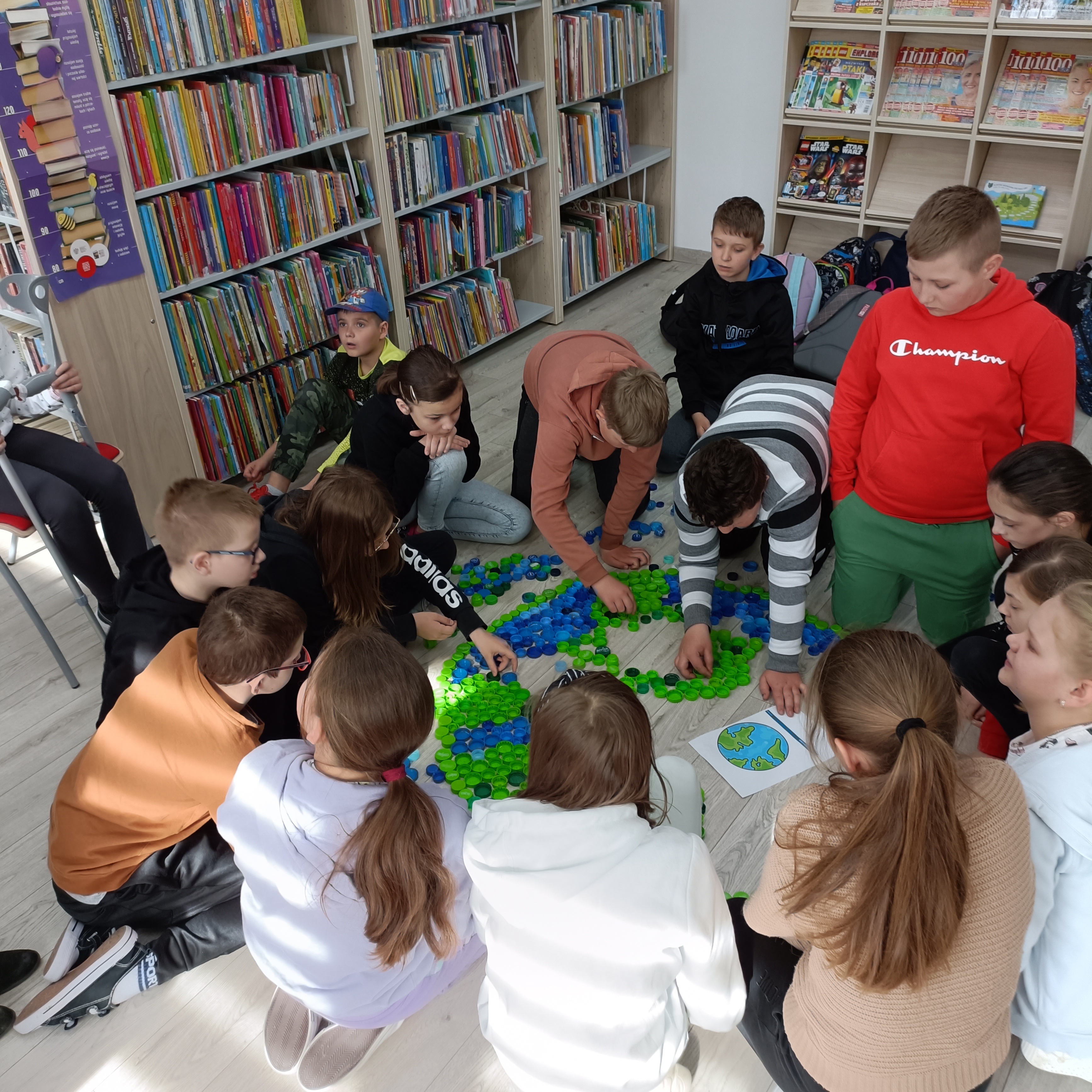 Uczniowie klasy czwartej wykonujący makietę Ziemi z plastikowych nakrętek.